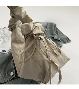 Detail of beige nylon crossbody bag featuring drawstring design and pleated fabric texture