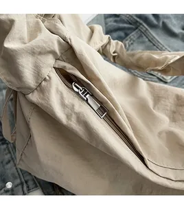 Detailed macro view of a smooth silver metal zipper on a beige nylon handbag texture