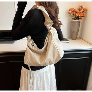 Close-up of wide pleated shoulder strap on a beige nylon tote bag for women