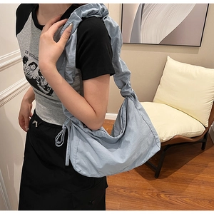 Close-up of light blue nylon hobo bag featuring decorative ruched strap and drawstring detail