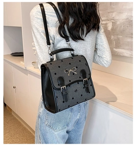 Close-up of grey polka dot backpack with embroidered bow and metal hardware detail