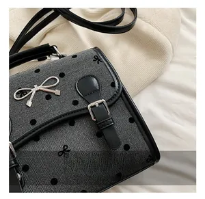 Close-up of charcoal grey polka dot fabric with black leather strap and silver bow detail