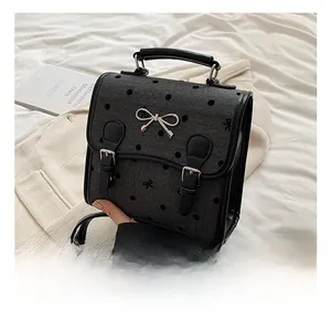 Detail shot of the black polka dot PU leather backpack with a silver metal bow buckle