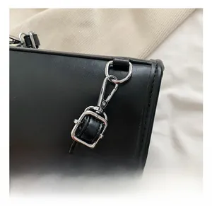 Close-up of adjustable shoulder strap with silver metal buckle on a black leather backpack