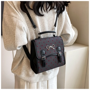 Detail view of small grey backpack with red heart patterns and silver bow buckle accessory