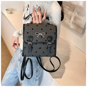 Detail view of the gray polka dot backpack with silver bow hardware and black straps