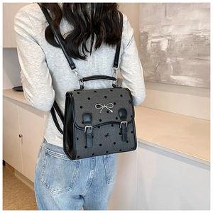 Detail of grey polka dot backpack with bow embroidery and metal butterfly charm