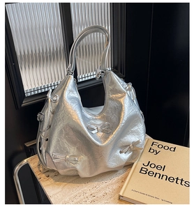 Detail of silver metallic tote bag featuring pleated texture and 3D bow accents