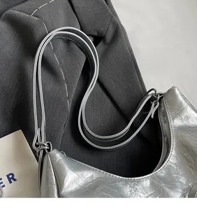 Detail of silver crescent bag featuring wrinkled metallic texture and metal zipper