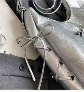 Close-up of silver wrinkled texture leather hobo bag with side bow and lacing detail