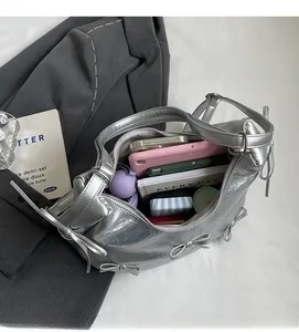 Spacious interior of silver bow tote bag showing daily items like notebooks and phone