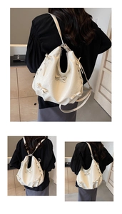 Detail of ivory pleated tote bag showing decorative bows and versatile shoulder straps