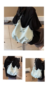 Detail of light blue wrinkled leather hobo bag featuring decorative 3D bow and soft texture