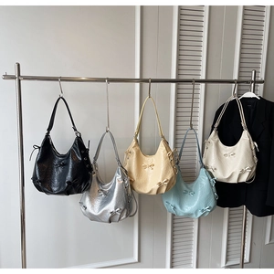 Detail of five colorful hobo bags with decorative bows on an industrial display rack