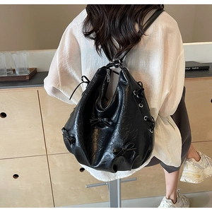 Detail of black wrinkled PU leather tote bag with decorative bows and silver zipper closure