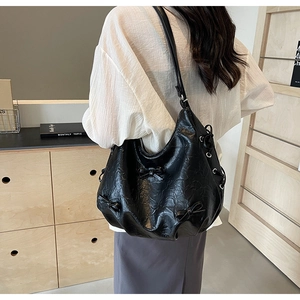 Detail of black bow shoulder bag with textured leather and side eyelet details