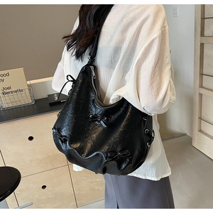 Detail view of the black wrinkled leather tote bag featuring stylish ribbon decorations
