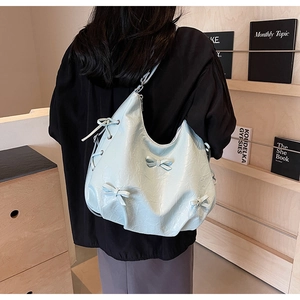 Close-up of light blue tote bag featuring 3D bow details and pleated leather texture