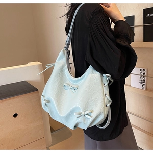 Close-up of light blue pleated tote bag with ribbon bows and drawstring metal eyelets