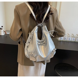 Detail of silver metallic tote with pleated texture and bow accents on model