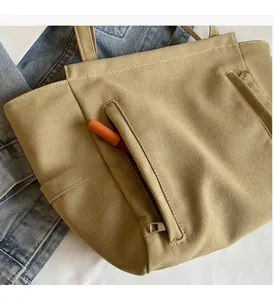 Detail of canvas tote bag with front zipper pocket showing storage for lipstick