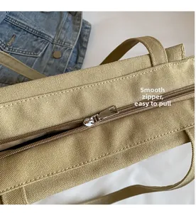 Close-up of smooth silver metal zipper on khaki canvas tote bag with neat stitching