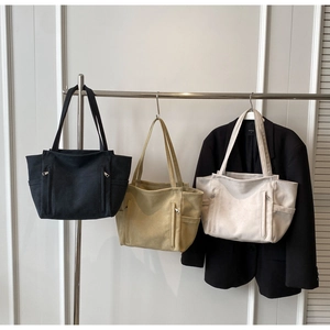 Hanging display of large canvas tote bags in black, khaki, and cream colors
