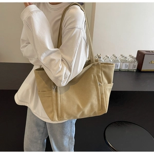 Detail of khaki canvas tote bag showing side pocket and front zipper on shoulder strap bag