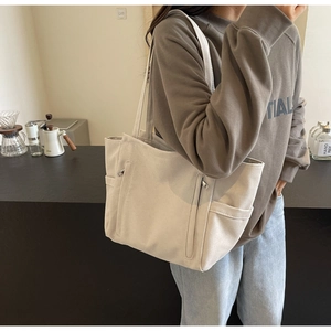 Canvas tote bag with vertical zipper pockets shown in a casual lifestyle setting