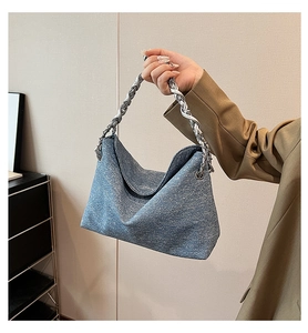 Detail of blue denim textured bag featuring a chunky silver chain handle and soft fabric