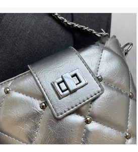 Detail der silbernen Stepptasche mit Metallic-Textur und Drehverschluss aus Metall