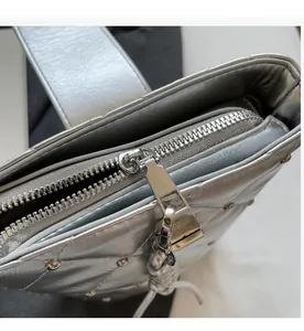 Detailansicht der silbernen Stepptasche mit glattem Metallreißverschluss und Nieten