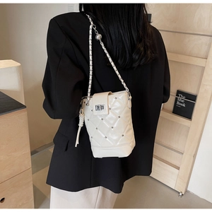 Detail der cremefarbenen Stepptasche mit Nieten und Kettenriemen am Modell