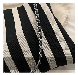 Detail of black and white striped tote with silver metal chain and leather strap