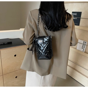 Detail einer schwarzen Stepptasche mit silbernen Nieten und Kettenriemen am Model