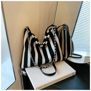 Detailed shot of vertical striped canvas tote bag with metal chain and leather strap