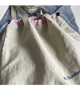 Detail of drawstring bucket bag with pink trim and blue 'My Sunday' logo print