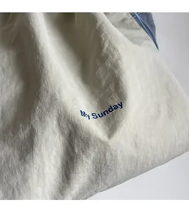 Detail of minimalist cream canvas bag featuring My Sunday blue printed lettering