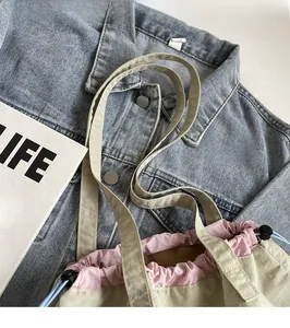 Detail of the reinforced shoulder strap and pink lining on a beige drawstring tote bag