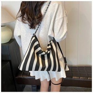 Close-up of black and white striped tote bag featuring silver chain and leather straps