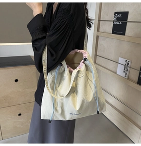 Detail of a beige canvas tote bag with pink drawstring and My Sunday print on a shoulder