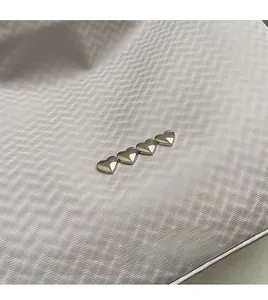 Macro shot of silver heart-shaped metal accents on textured champagne violet fabric