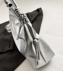 Detail of silver metallic bucket bag with knot shoulder strap and high-quality stitching