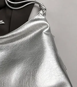 Detail shot of metallic silver tote bag featuring knotted strap and textured soft leather