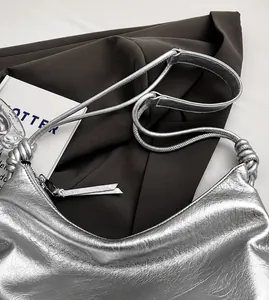 Detail of silver metallic tote bag featuring knotted handle and wrinkled texture surface