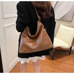 Detailed view of large caramel brown leather hobo bag with unique strap knot decoration