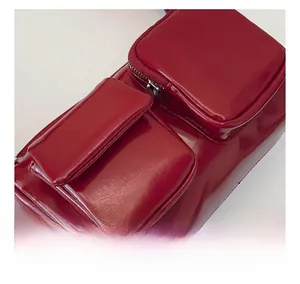 Detail shot of the glossy dark red PU leather surface and functional zipper pockets