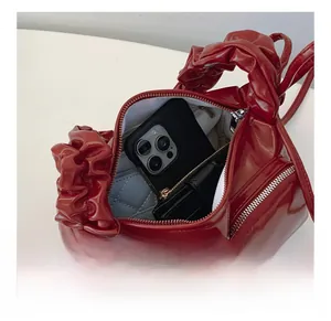 Interior capacity detail of burgundy patent leather crescent bag showing phone storage