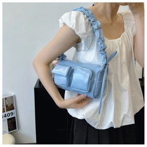 Detail of light blue PU leather shoulder bag featuring ruffled straps and 3D utility pockets