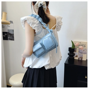 Detail of light blue pleated strap and functional side pockets on this chic shoulder bag
